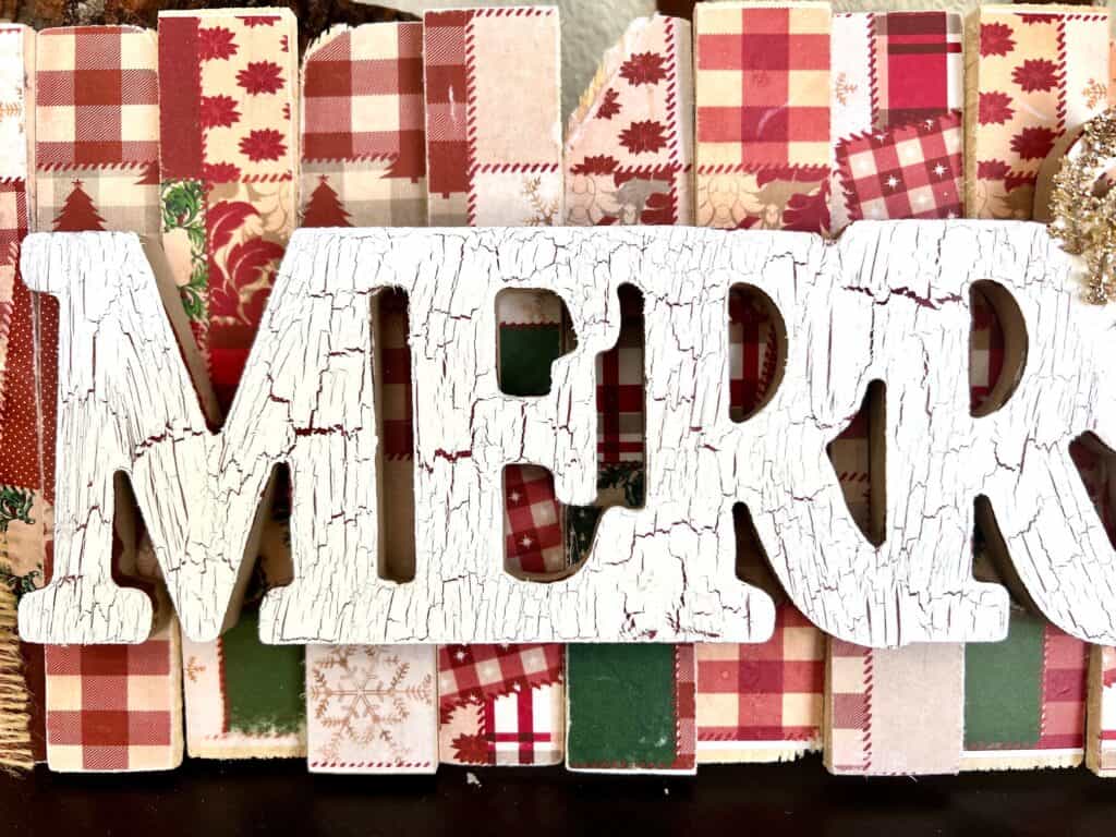 The wooden word merry painted with the crackle technique with red and white paint.
