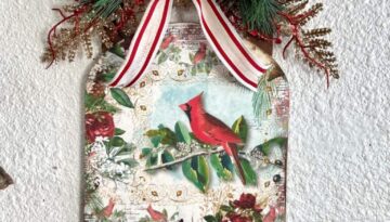 Dollar Tree Wooden Sled makeover for Christmas with a red cardinal rice paper print mod podged to the front, with greenery and a read and white striped bow and bling in the center for a Christmas Vintage DIY decor feel.
