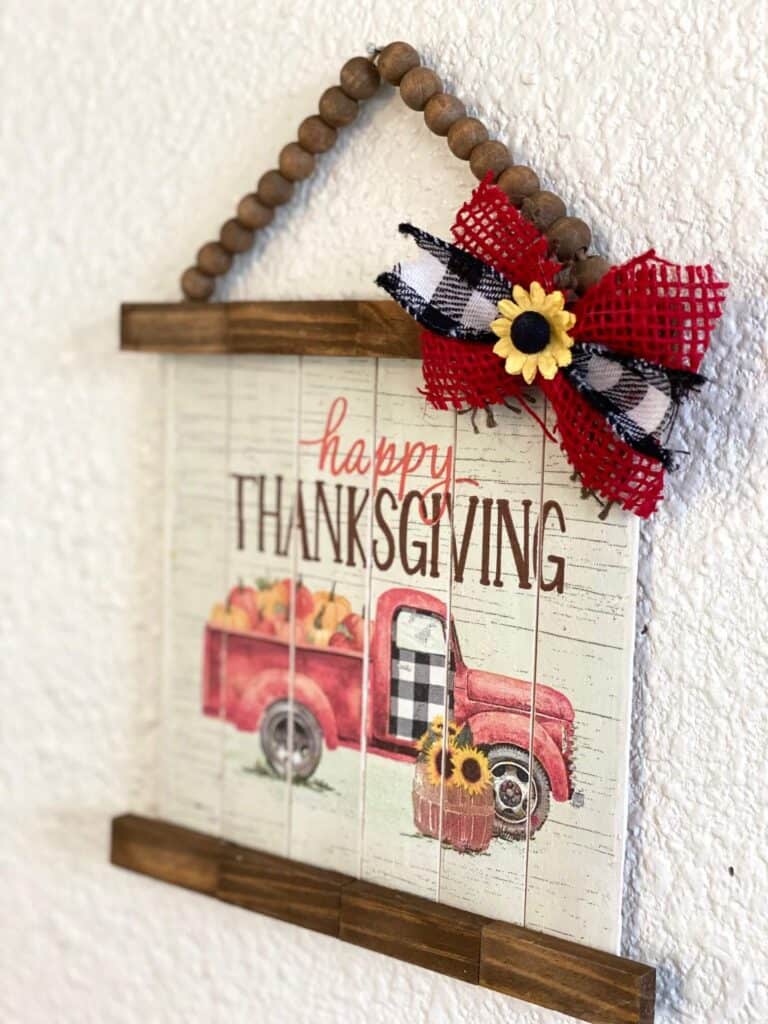 Happy Thanksgiving Napkin Decor made with a red truck napkin decoupaged to paint sticks to look like slats with a cute bow and sunflower and wood bead hanger.