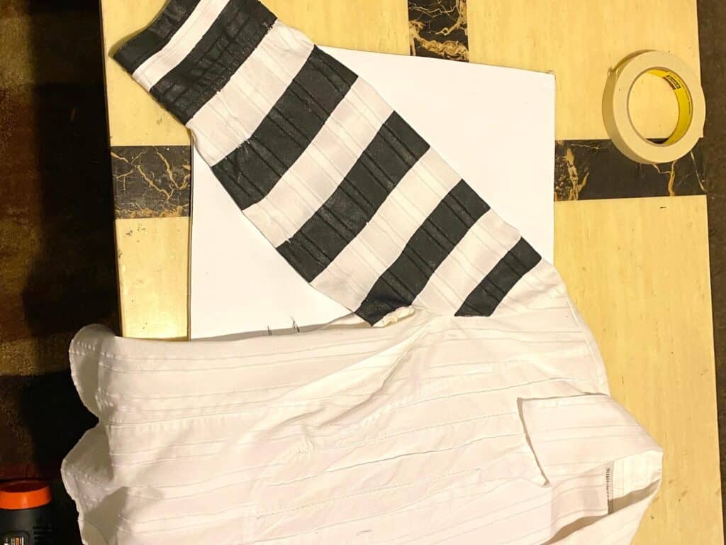 White shirt with the right sleeve painted with black and white stripes.