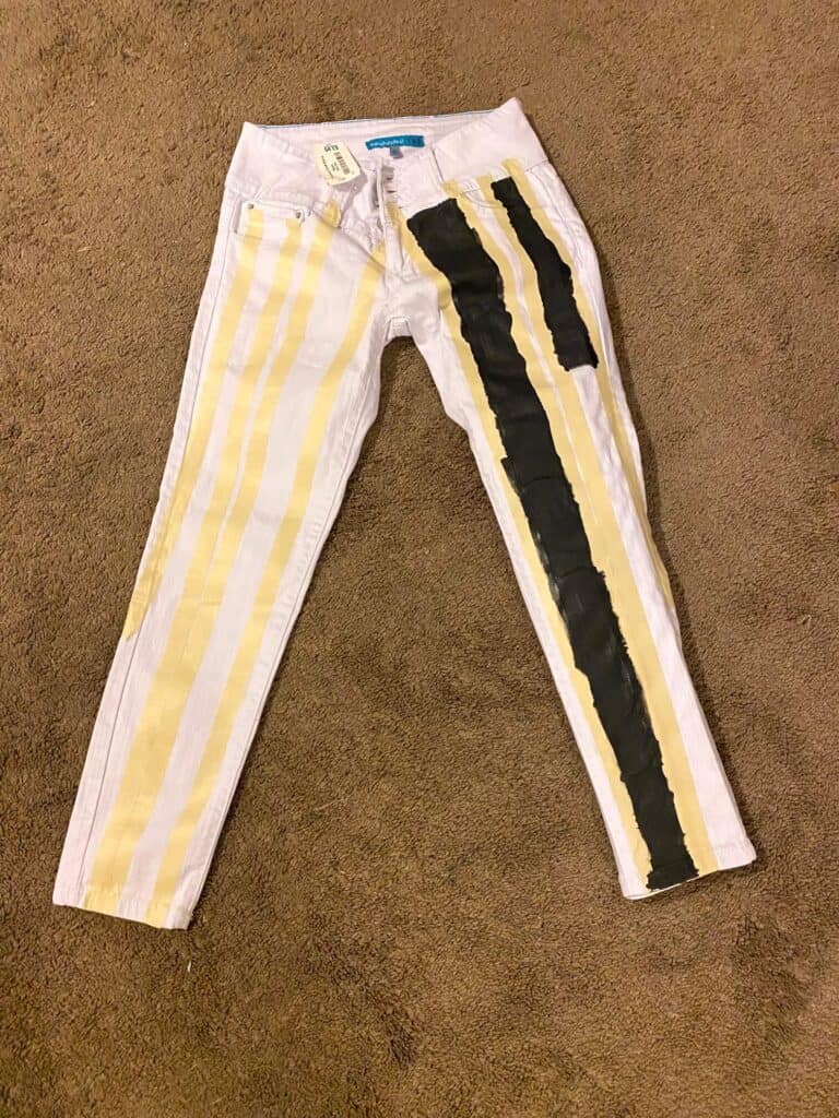 White pants that are taped off to make stripes with the left pant leg partially painted with black stripes.