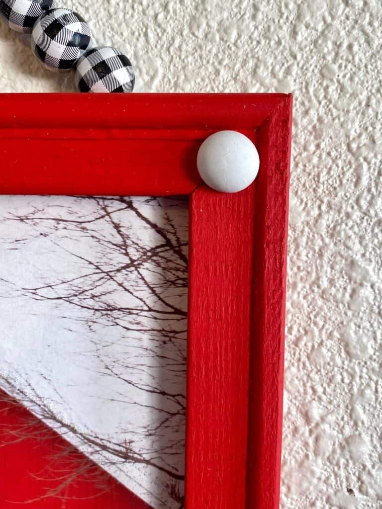 The wooden frame of the project painted all bright red with a white half wood bead in each corner.