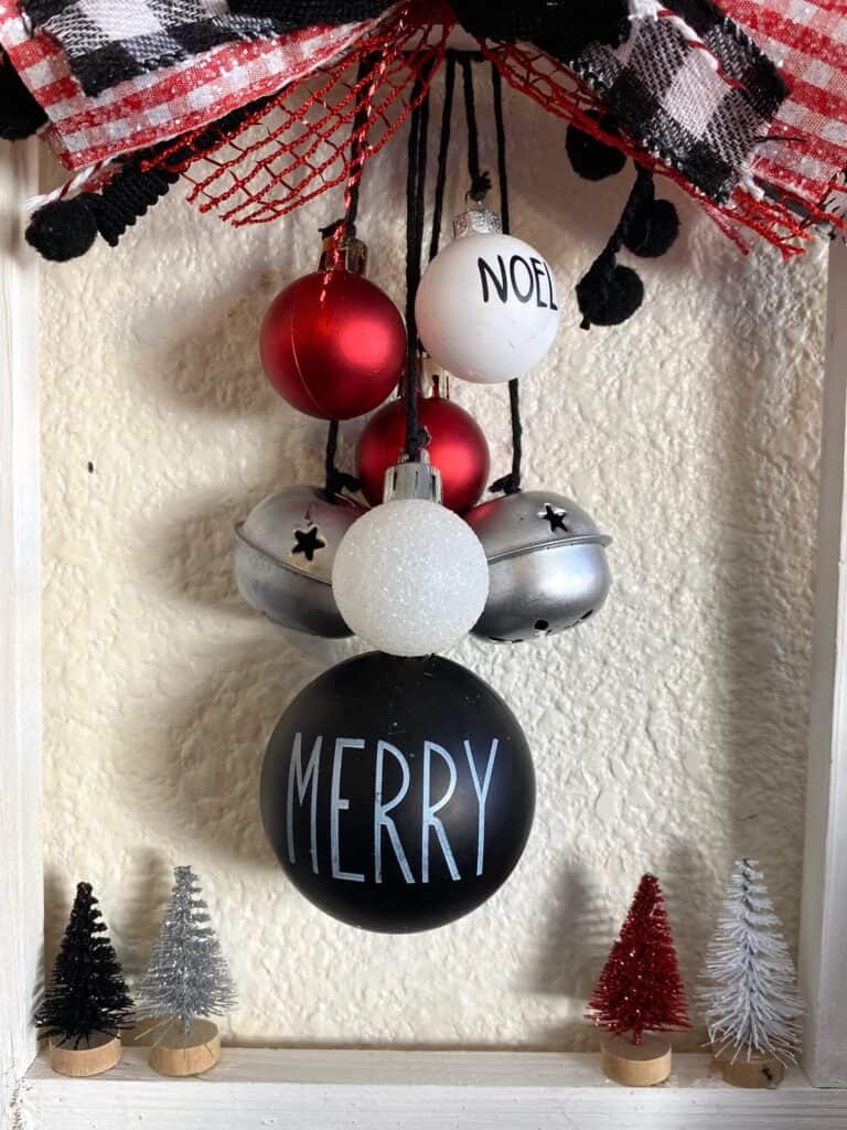 The rae dunn inspired red, black, and white ornaments hanging from black twine down the center of the canvas.