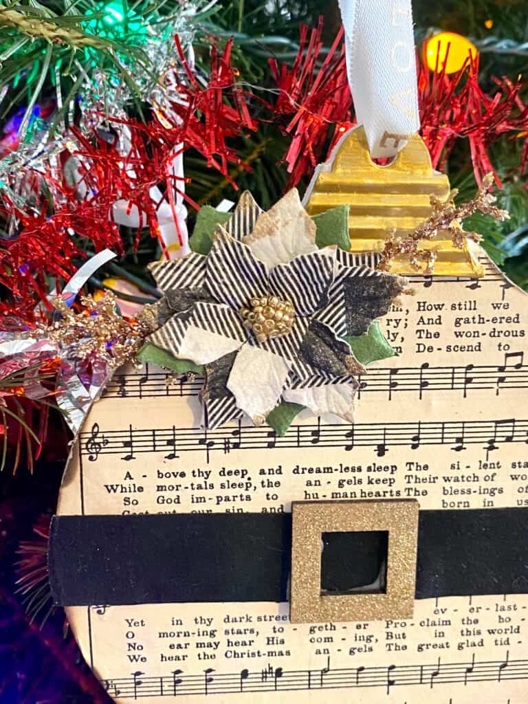 Black and white buffalo check green poinsettia with gold glitter branches at the top of the ornament.