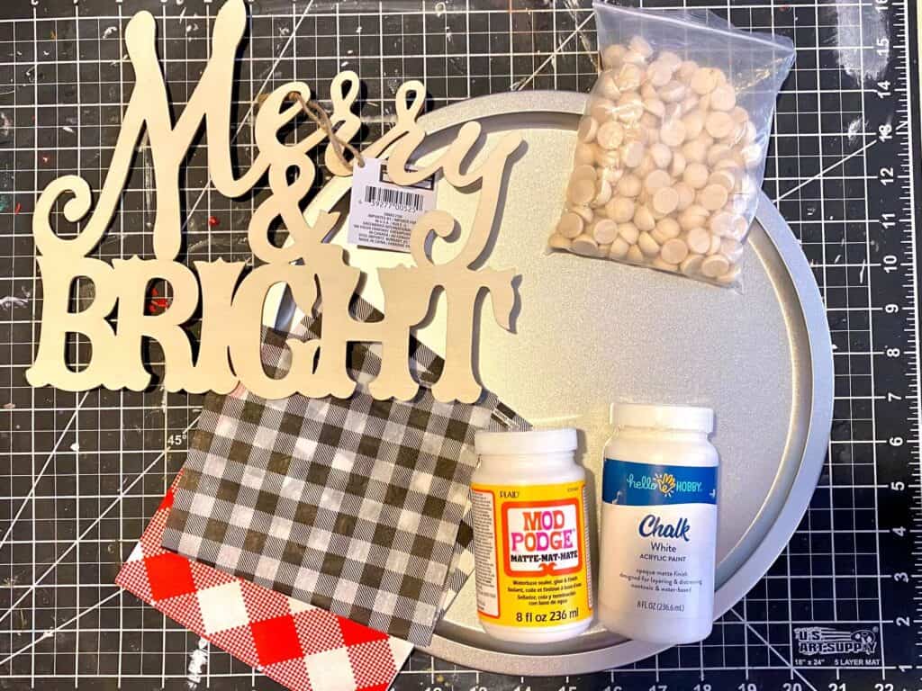 Supplies needed to make a christmas pizza pan crafy with a dollar tree Merry and Bright wood cutout, red and black buffalo check napkins and some paint and mod podge.