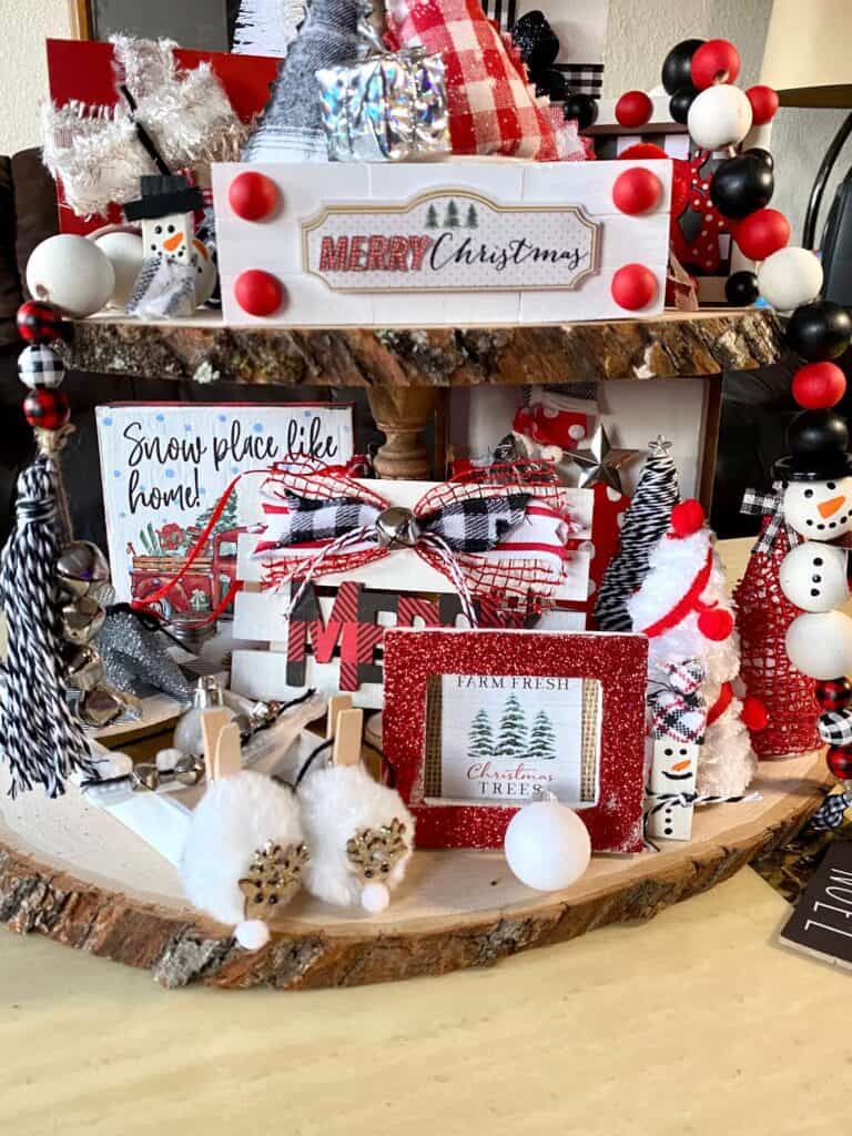 Bottom tier of the 3 tiered tray with an assortment of red, black, and white handmade Christmas decorations.