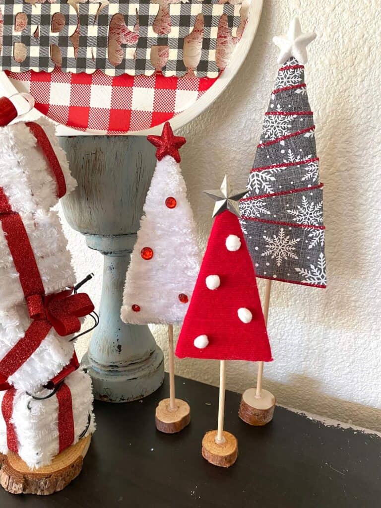 Red, white, and grey yarn and ribbon wrapped cardboard Christmas trees with star toppers and a wood dowel trunk with wood round base. Easy, affordable, DIY Christmas decor made with recycled material.