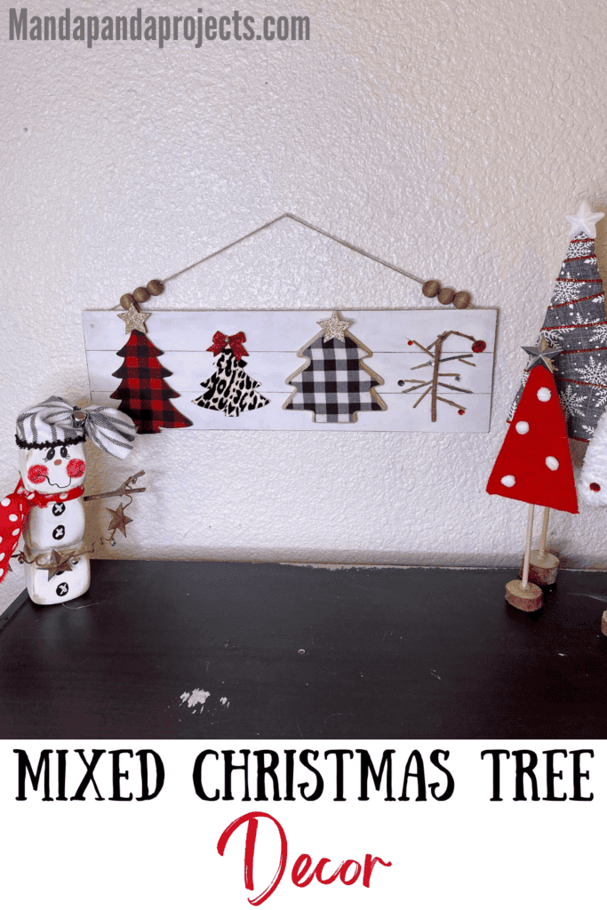 Mixed Christmas tree sign on a long wooden faux shiplap background with red and black buffalo check christmas tree, black and white buffalo check tree, leopard print tree, and a charlie brown christmas tree with a partial wood bead hanger displayed on the wall for DIY Christmas decor.