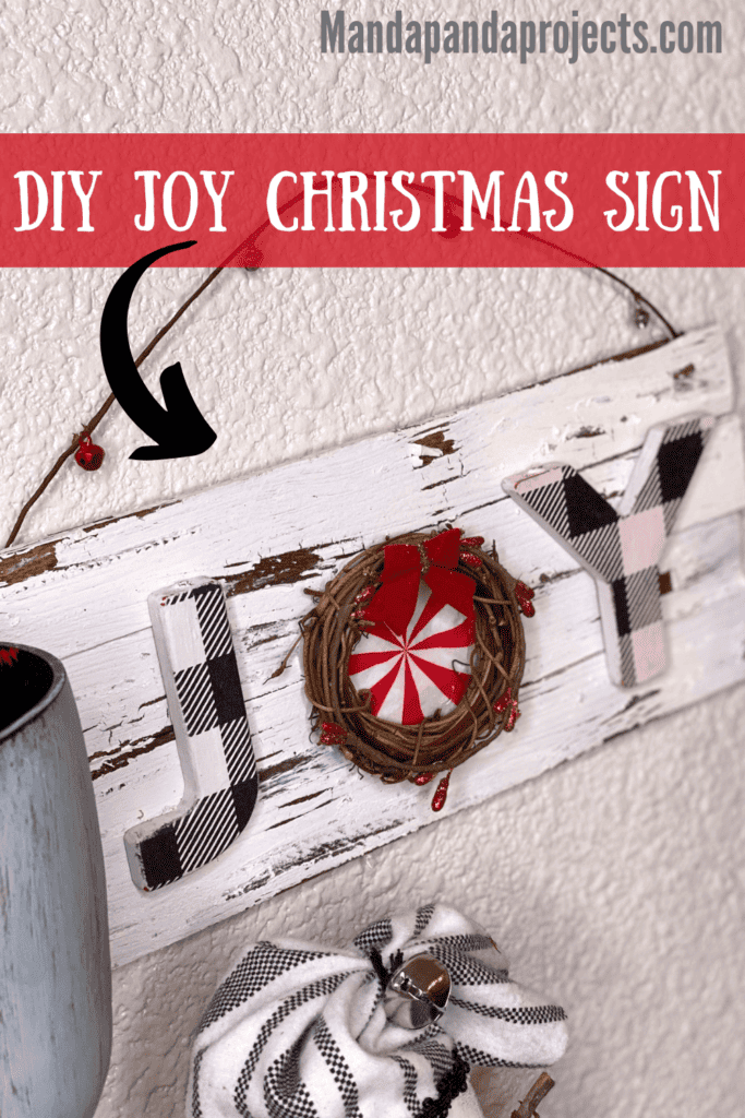 DIY JOY Christmas Sign on a white distressed chippy background with the O as a grapevine wreath with a peppermint napkin inside and a berry wired garland hanger.