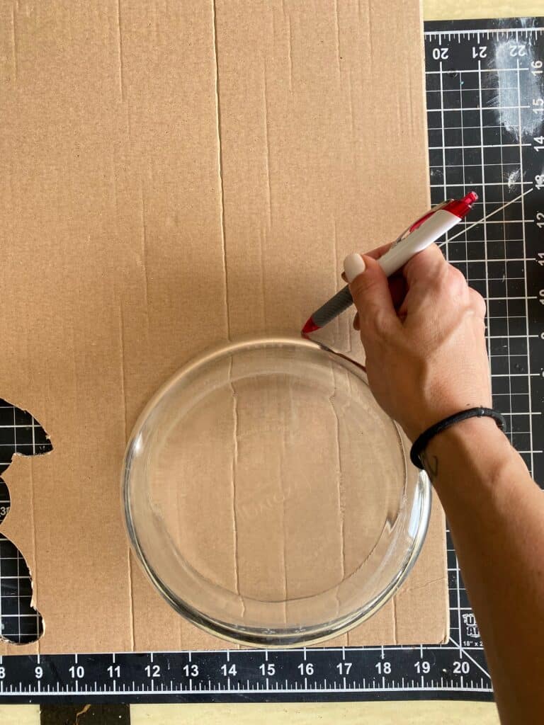 A bowl being traced onto a piece of cardboard to get a perfect circle.