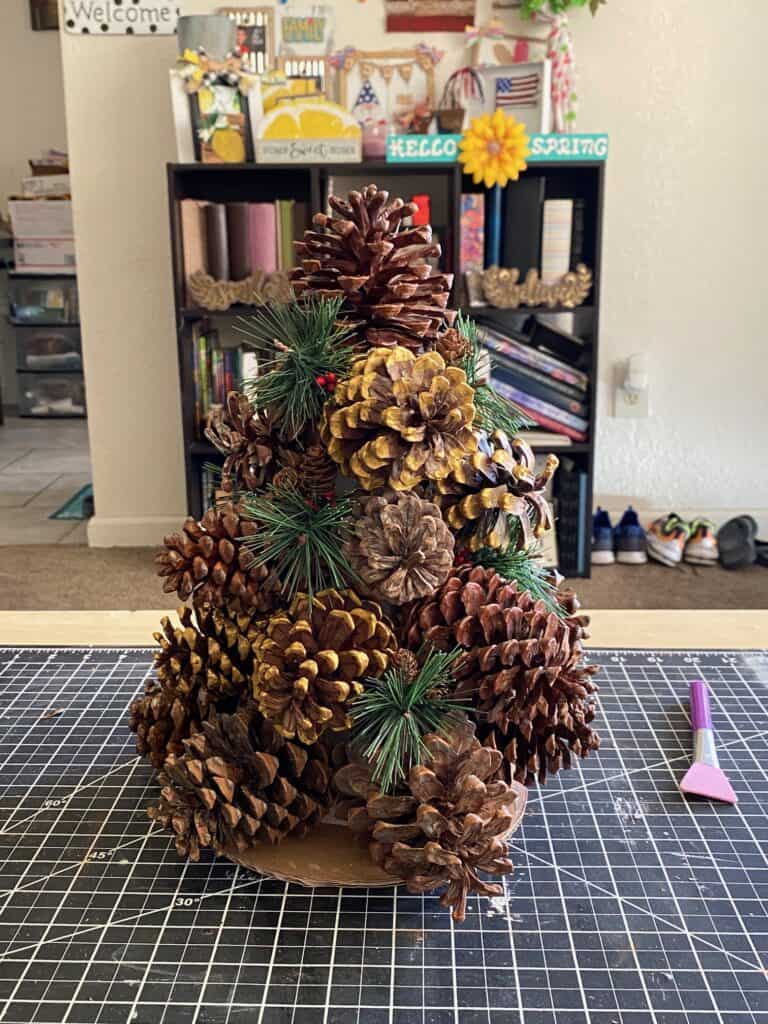 Greenery picks stuck in all the gaps of the pine cones so that you can't see the white of the foam cone.