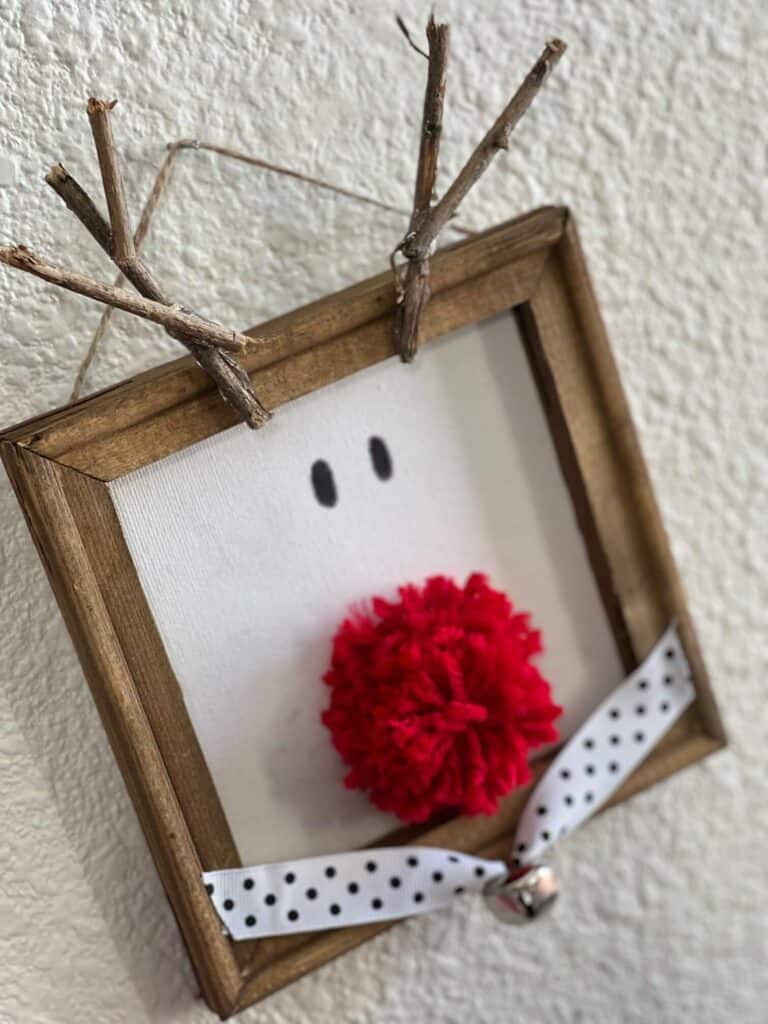 Side view of the stretched canvas with yarn pom pom nose and a black and white polka dot collar.