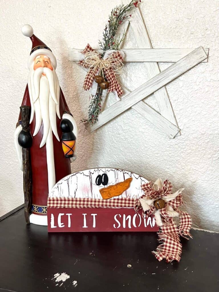 Tall vintage looking santa statue, rustic christmas paint stick star hanging on the wall, staged with the completed snowman project sitting on a bookshelf.