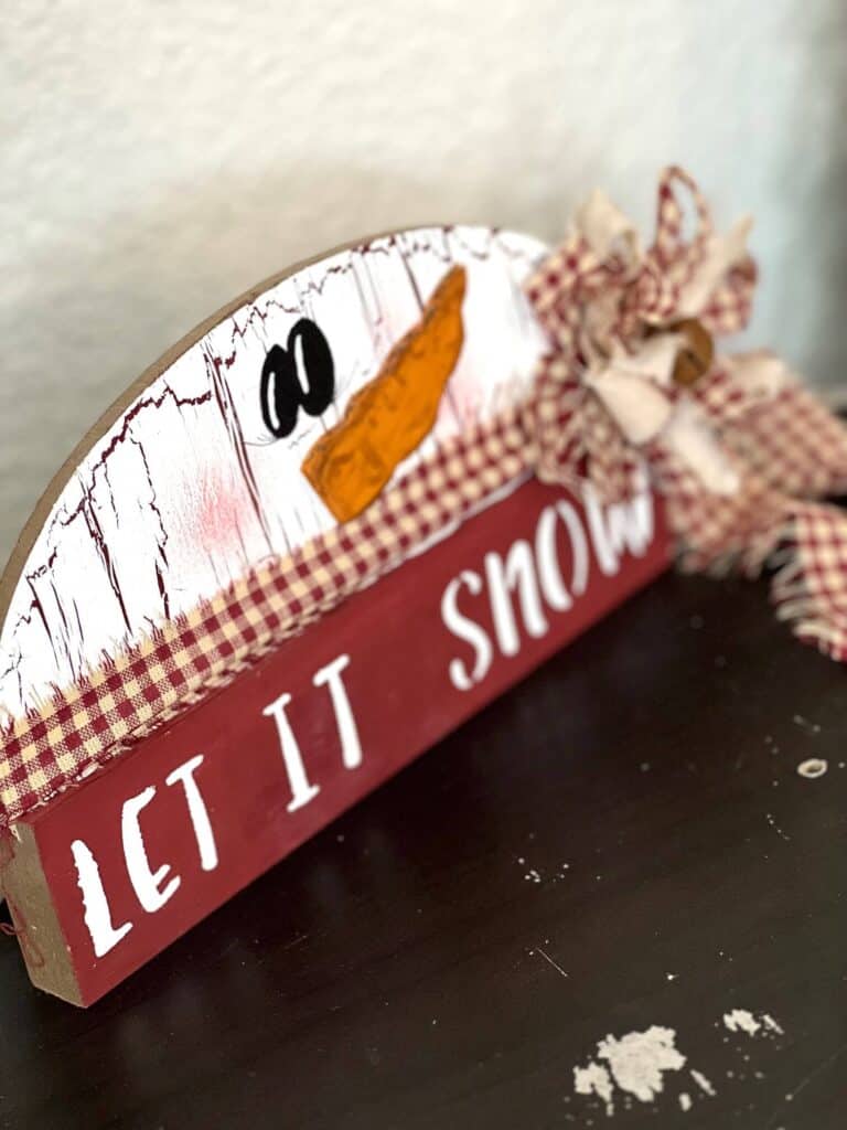 Side Portrait of the half wood snowman that says "let is snow".