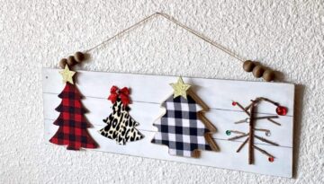 Mixed Christmas tree sign on a long wooden faux shiplap background with red and black buffalo check christmas tree, black and white buffalo check tree, leopard print tree, and a charlie brown christmas tree with a partial wood bead hanger displayed on the wall for DIY Christmas decor.