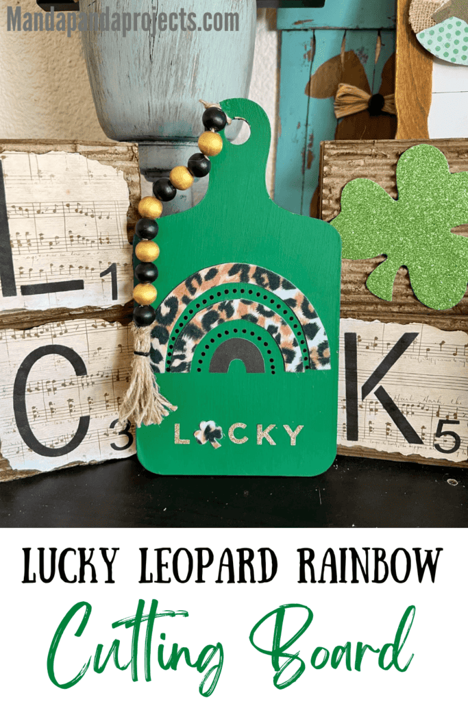 LUCKY Leopard Rainbow Cutting Board for St. Patricks Day with a black and leopard rainbow, the word LUCKY where the "U" is a shamrock, and a gold and black beaded garland on top. Easy to make DIY St Patty's Day decor.