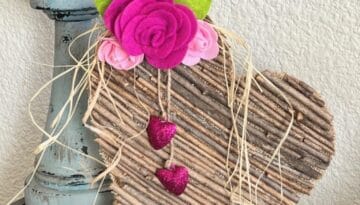 Rustic Valentines Day Stick Heart DIY Decor with felt roses and hanging pink sparkly hearts and raffia.