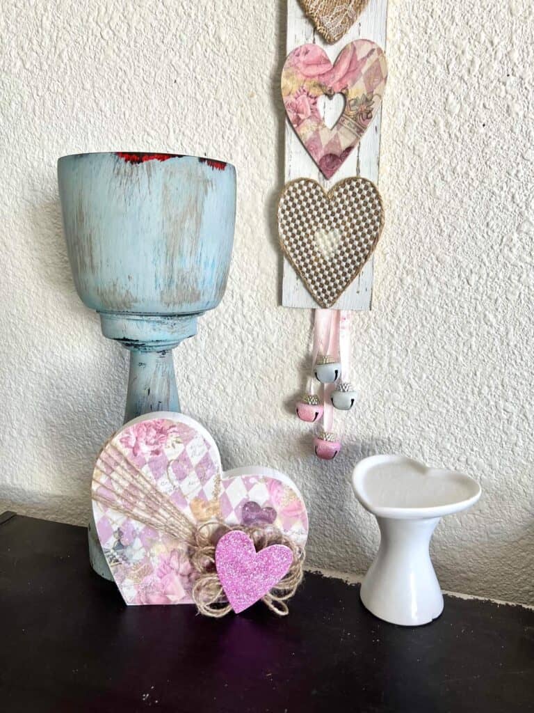 The chunky heart with rice paper printable mod podged onto it, sitting on a bookshelf underneath a long wood sign with 3 vintage hearts.