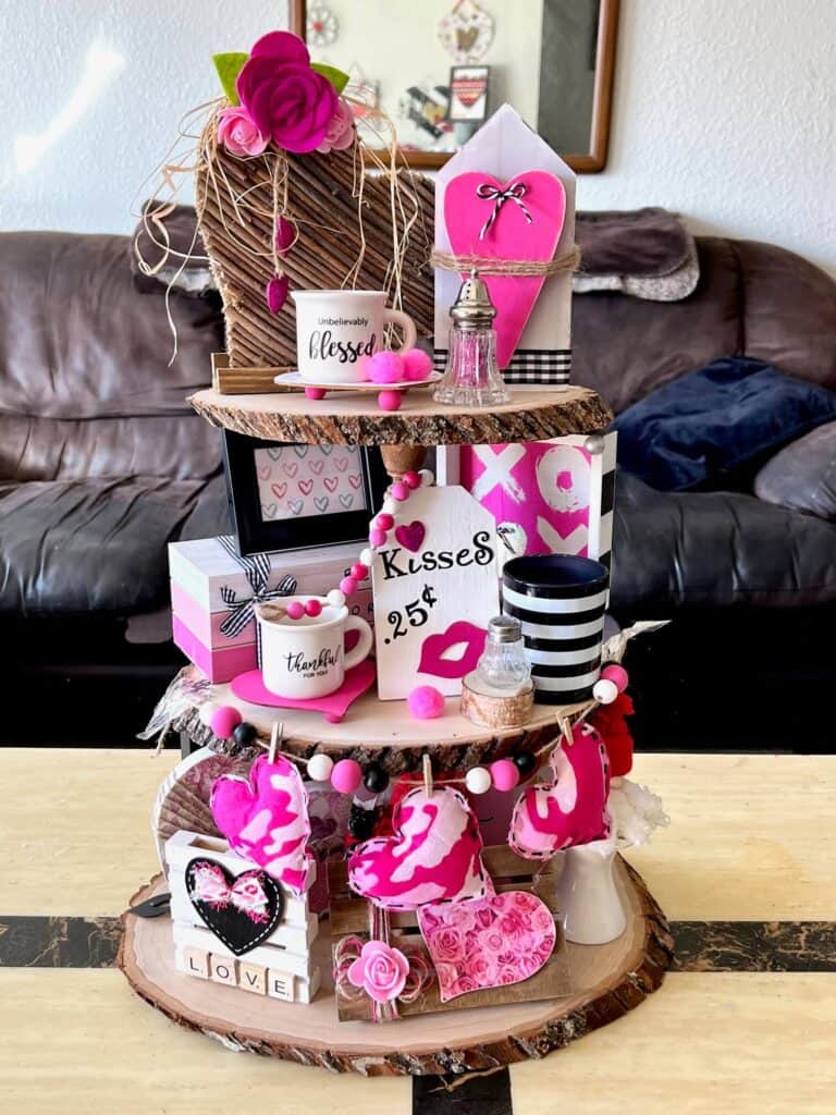 Valentines themed tiered tray with pink white and black handmade valentines decor on all three tiers.