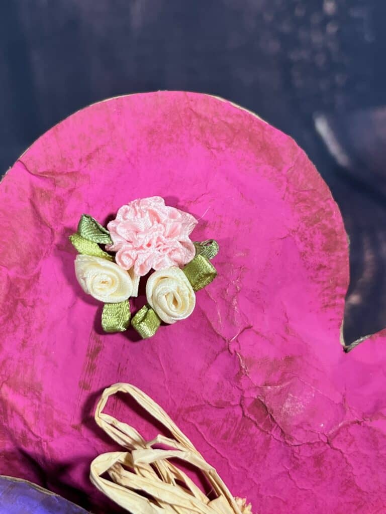 Creme and pink silk flowers glued to the top left of the pink completed heart.