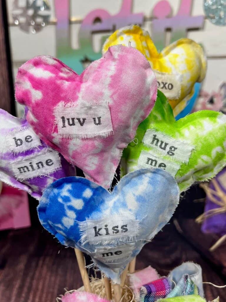 Close up of the stuffed hearts where you can see all the sayings stamped on them, saying "kuv u", "hug me", "kiss me", :be mine", "xoxo".