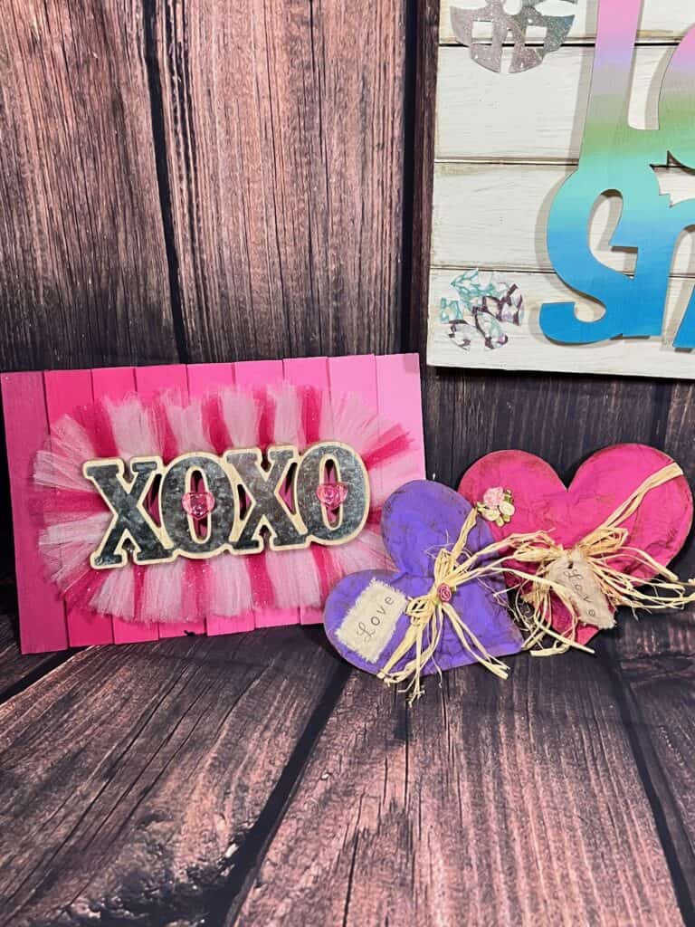 Pink ombre XOXO sign next to the pink and purple kraft paper hearts.