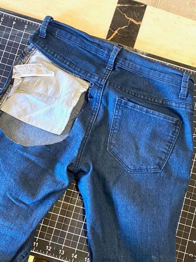 Pair of blue jeans with the pocket cut out of the butt.