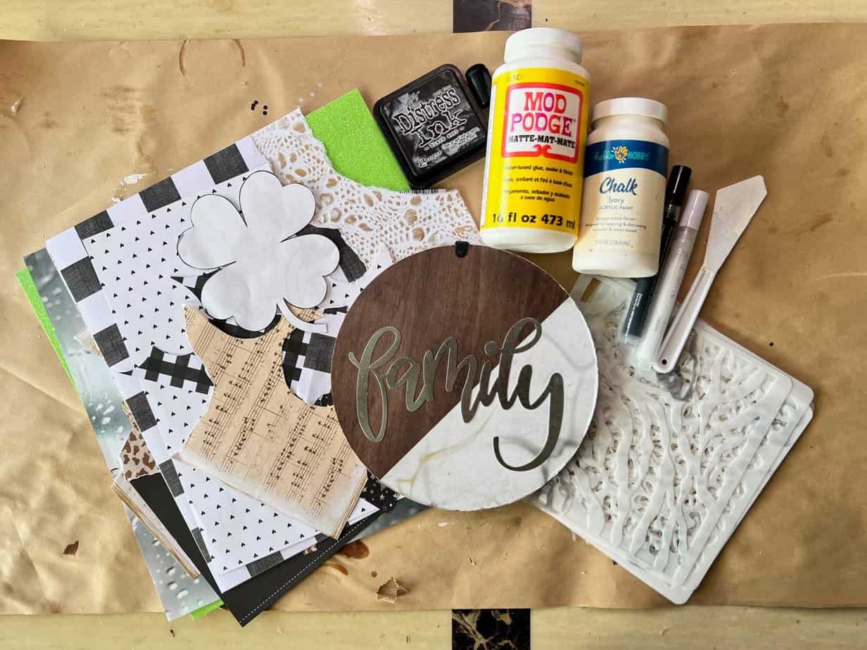 Supplies needed to make a 4 leaf clover with a dollar tree wood round, scrapbook paper, mod podge, paint, stencils, and ink.