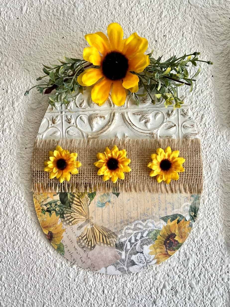Dollar Tree Sunflower wood Easter Egg made with a rice paper printable, a Dollar Tree wall tile, burlap, sunflowers and greenery for DIY easter decor.