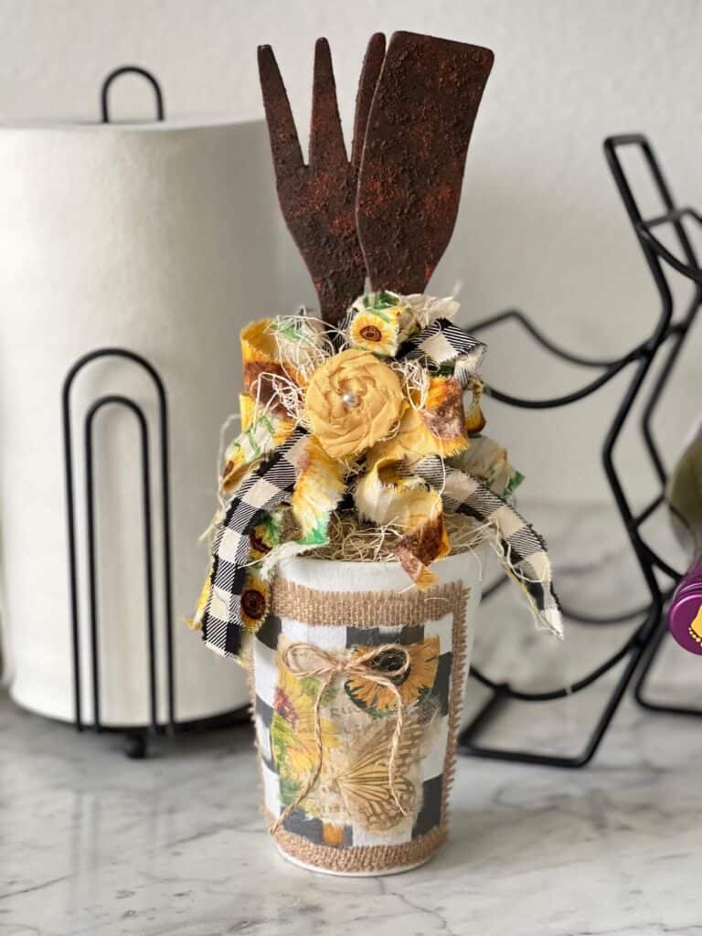 Rusted Utensil Kitchen Jar DIY Decor made with thrift store wood fork and spoon, vintage sunflower rice paper printable, burlap, buffalo check and a scrappy fabric bow for a Sunflower theme kitchen.