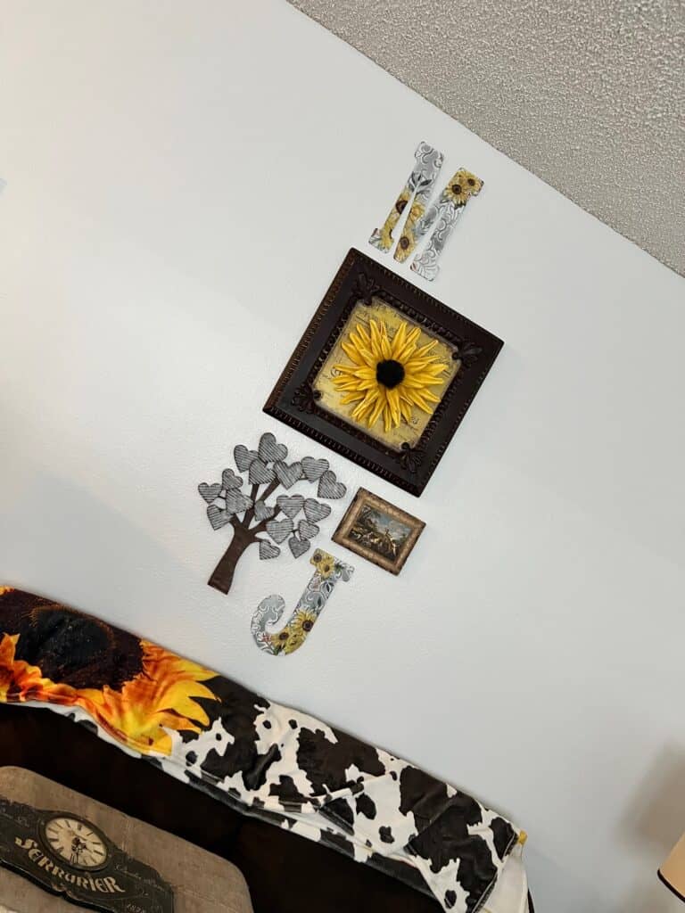 The main huge sunflower decor piece hanging on the wall with the metal heart tree underneath and the letters J and M.