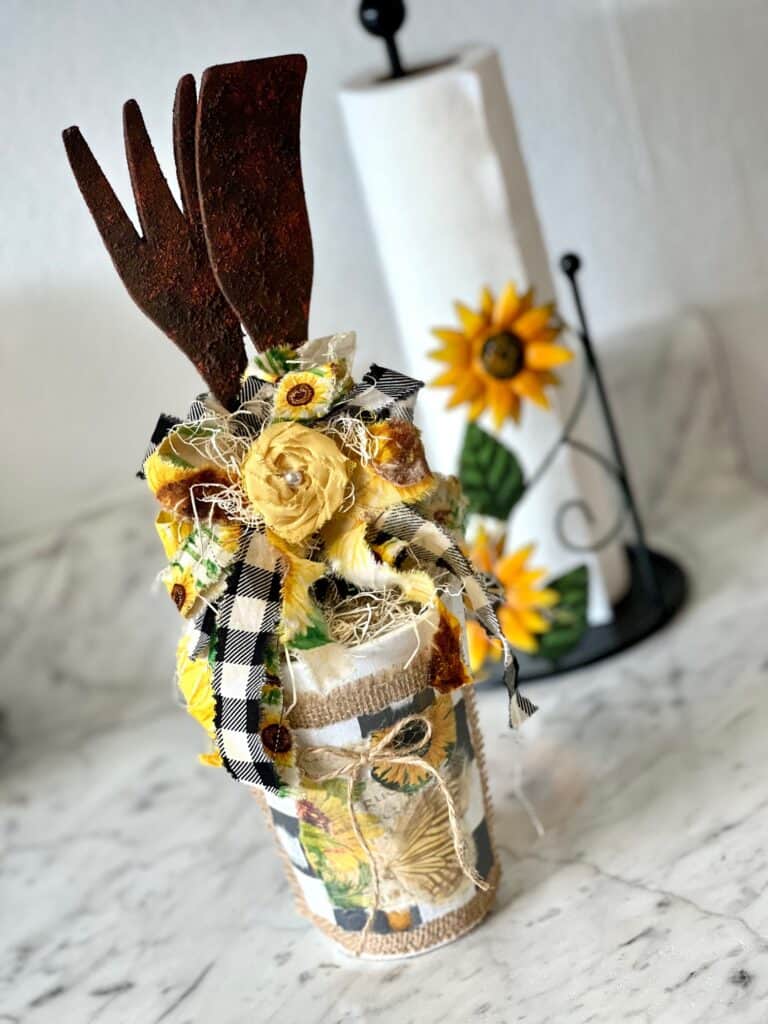 Rusted Utensil Kitchen Jar DIY Decor made with thrift store wood fork and spoon, vintage sunflower rice paper printable, burlap, buffalo check and a scrappy fabric bow for a Sunflower theme kitchen.