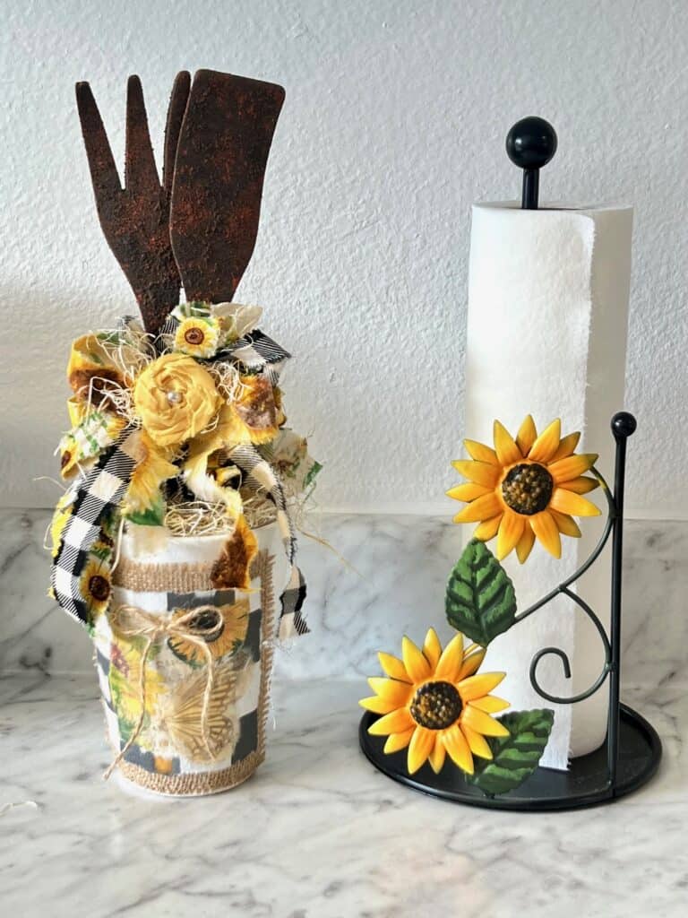 Rusted utensil jar with a big sunflower bow on the kitchen counter next to a sunflower paper towel holder.