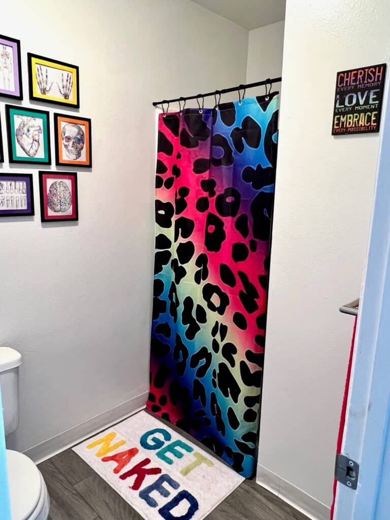 Colorful rainbow themed girls bathroom decorated in lisa frank inspired colors and decor like it's straight out of the 90's with thrift store and curated decor.