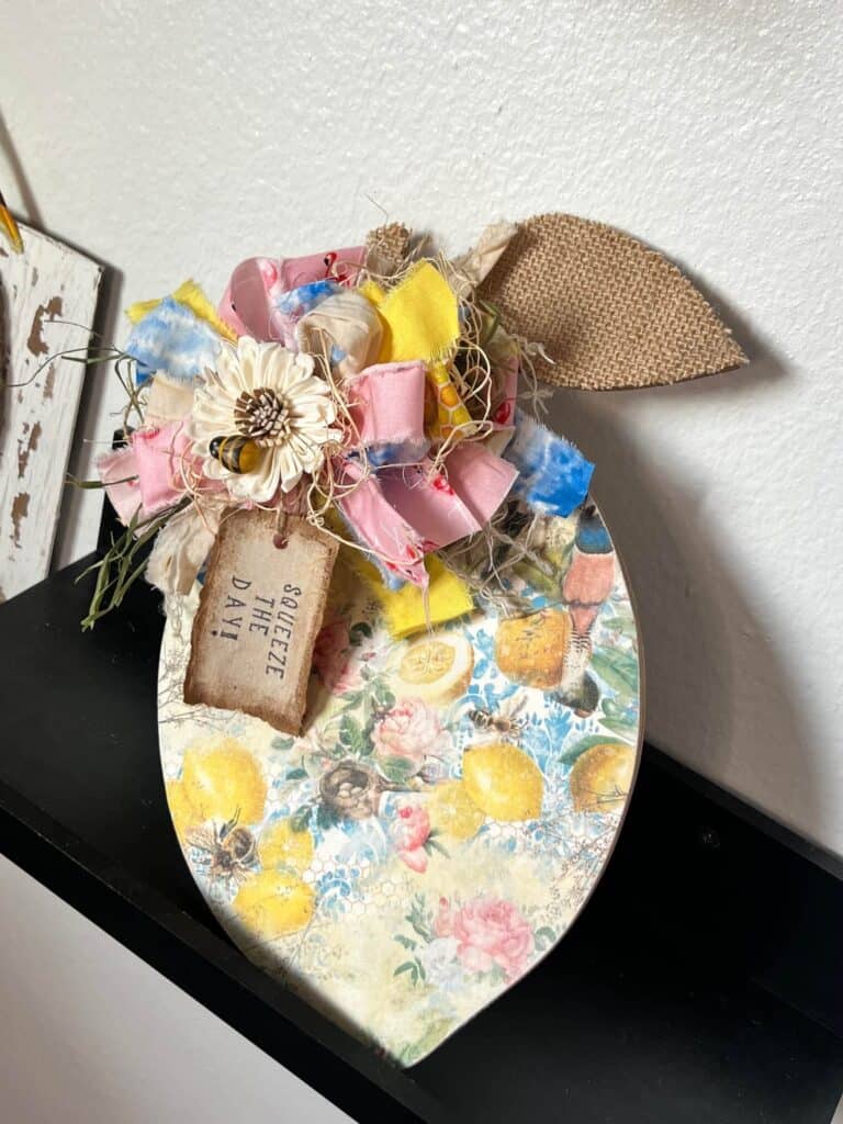 DIY Wood lemon cutout decor with blue, yellow, and pink  lemon woods rice paper and a big messy bow with a sola wood flower and mini bee embellishment and a burlap leaf for easy and affordable summer decor.