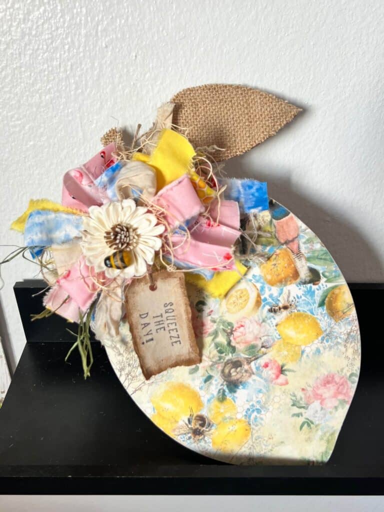 DIY Wood lemon cutout decor with blue, yellow, and pink  lemon woods rice paper and a big messy bow with a sola wood flower and mini bee embellishment and a burlap leaf for easy and affordable summer decor.