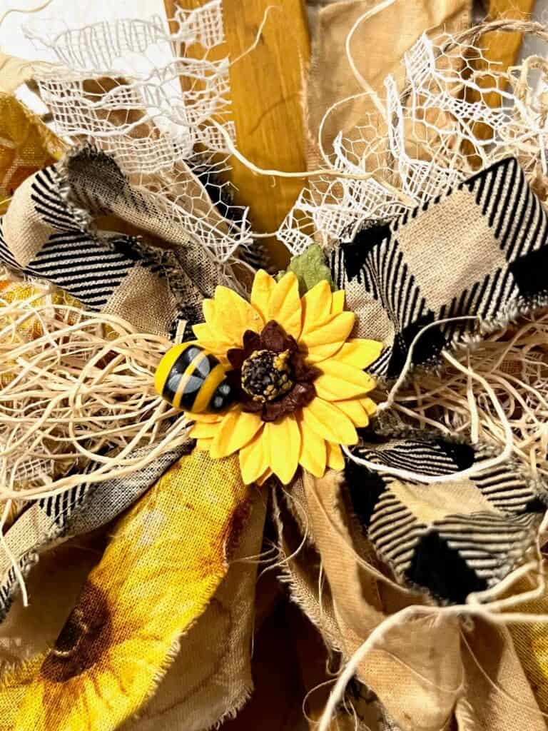 The center of the messy fabric ow with a sunflower and a bee.