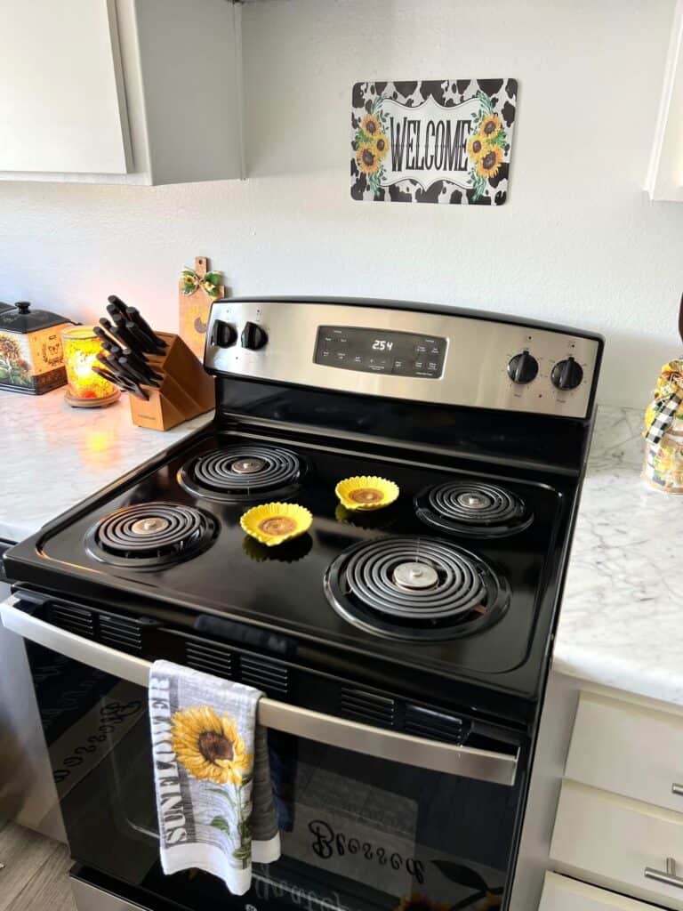 Kitchen stove with sunflower spoon rests and a kitchen towel hanging on the stove.