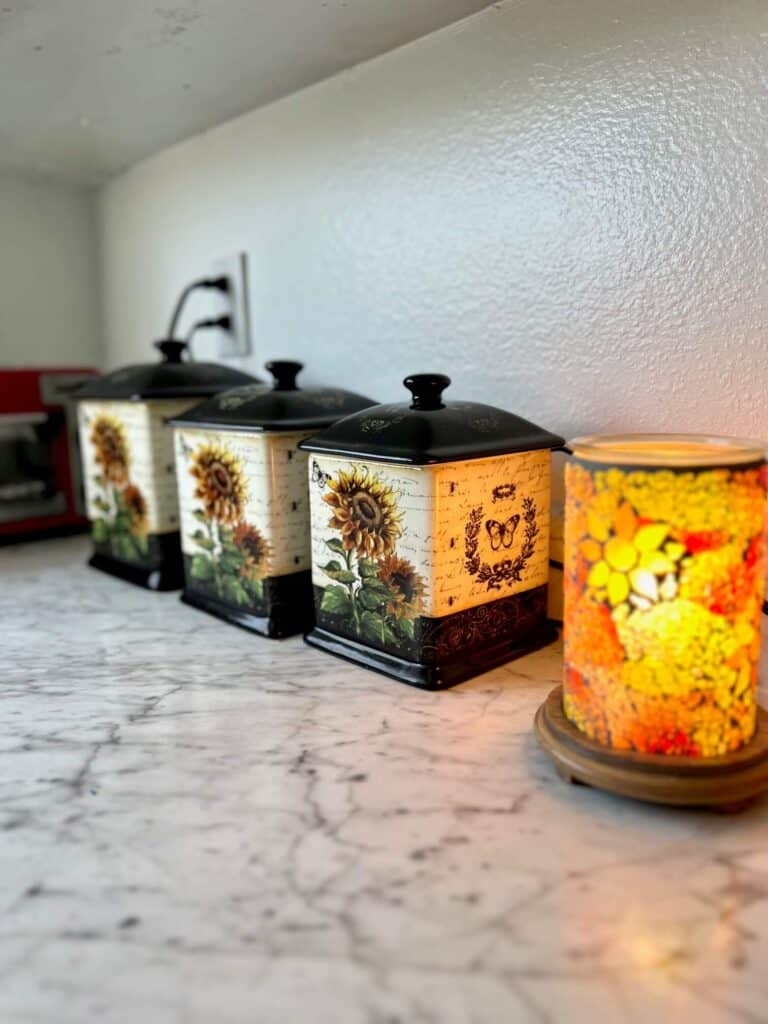Sunflower canisters on the kitchen counter next to a sunflower wax warmer.