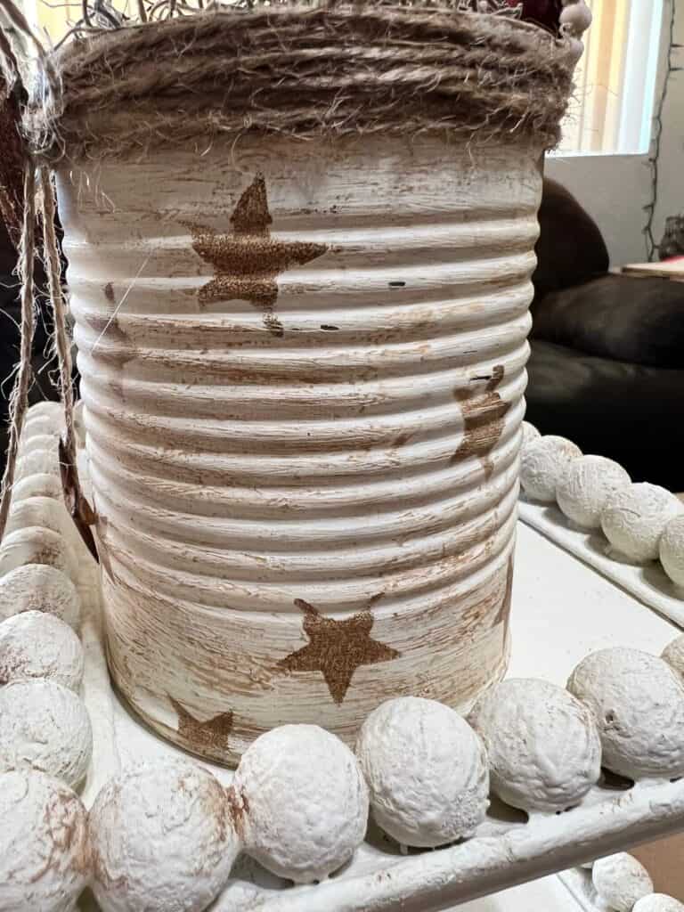 Recycled tin can painted white with antique wax stars with twine on the top.