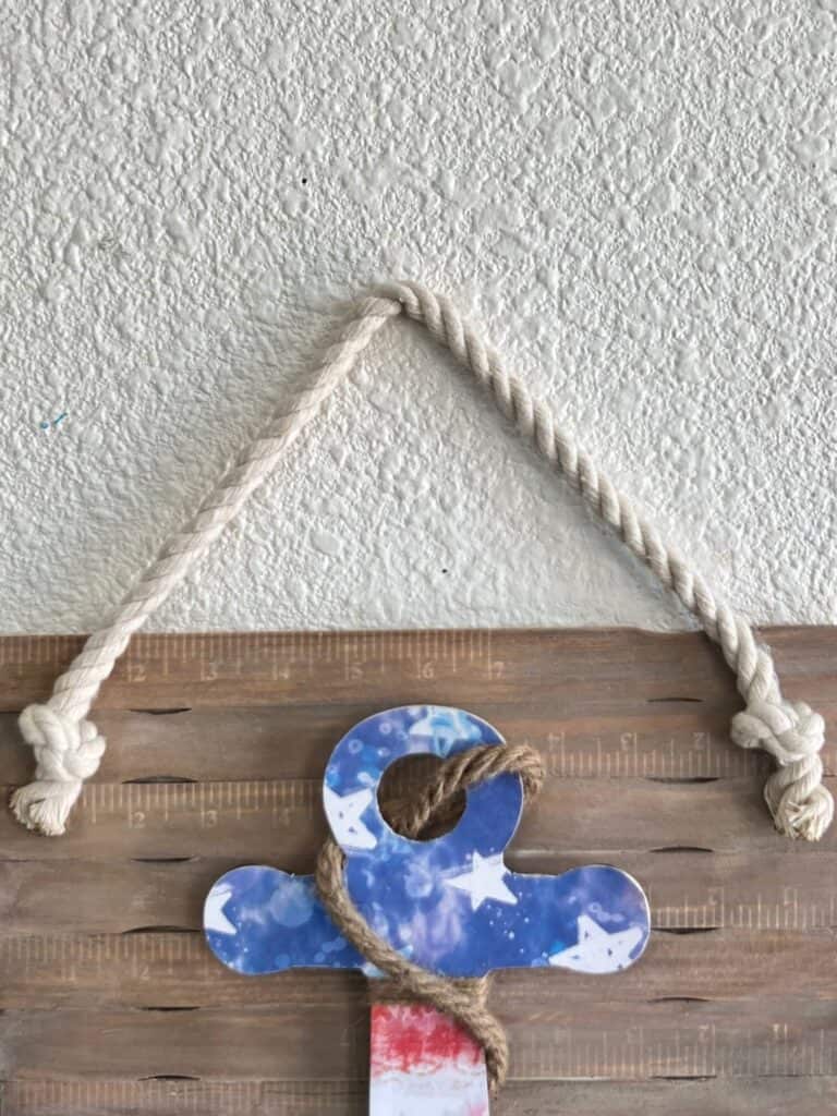 The american flag anchor project hanging on the wall with white nautical rope.