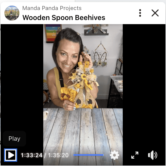 Amanda holding the completed Dollar Tree Wood Spoon Beehive on a Facebook Live replay.