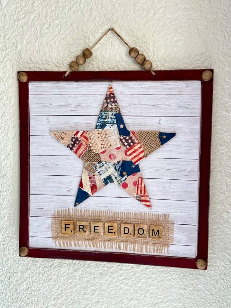 Patriotic Patchwork Star with red, white, and blue Americana scrapbook paper on a Dollar Tree surface with scrabble tile word freedom and a shiplap background for DIY Decor for the 4th of July.