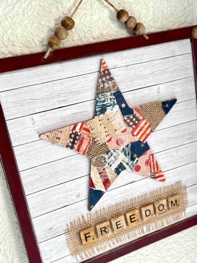 Patriotic Patchwork Star with red, white, and blue Americana scrapbook paper on a Dollar Tree surface with scrabble tile word freedom and a shiplap background for DIY Decor for the 4th of July.