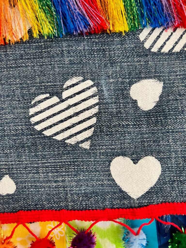 Various white hearts stenciled onto a piece of jeans denim.