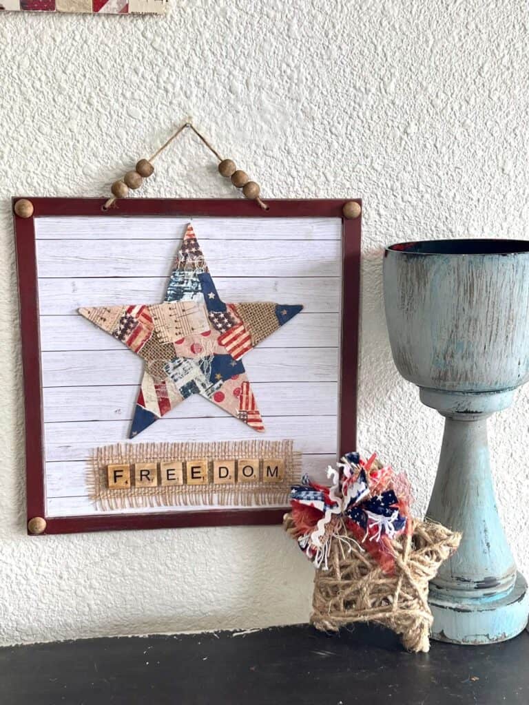 The completed project displayed hanging on the wall next to a chunky candlestick and a small twine star.