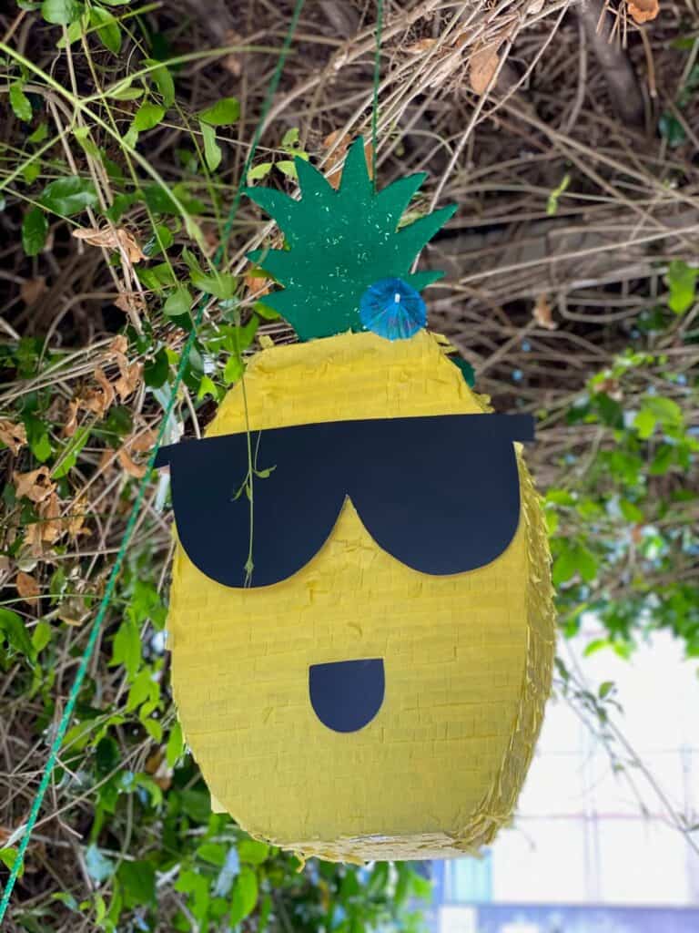 A pineapple themed piñata with sunglasses.
