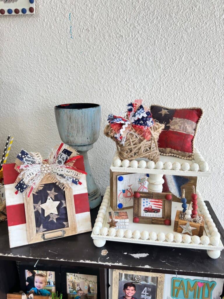 A set up of 4th of july red, white, and blue decor on a bookshelf.