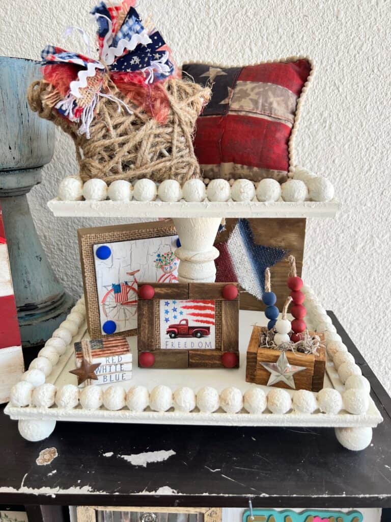White handmade patriotic americana 4th of july themed tiered tray with lots of decor on it.