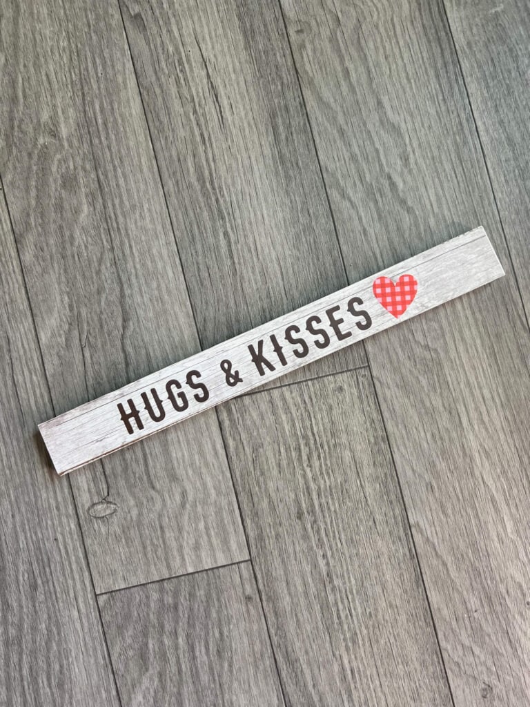 Long decorative board that says Hugs & Kisses
